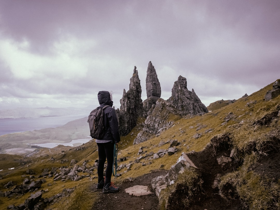 man in black jacket standing on rock formation during daytime