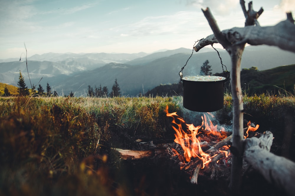 feu sur marmite noire sur un champ d’herbe verte pendant la journée