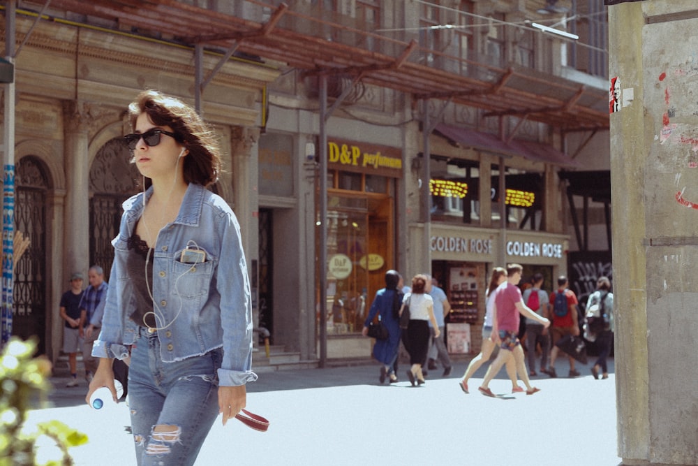 woman in blue denim jacket and blue denim jeans walking on street during daytime