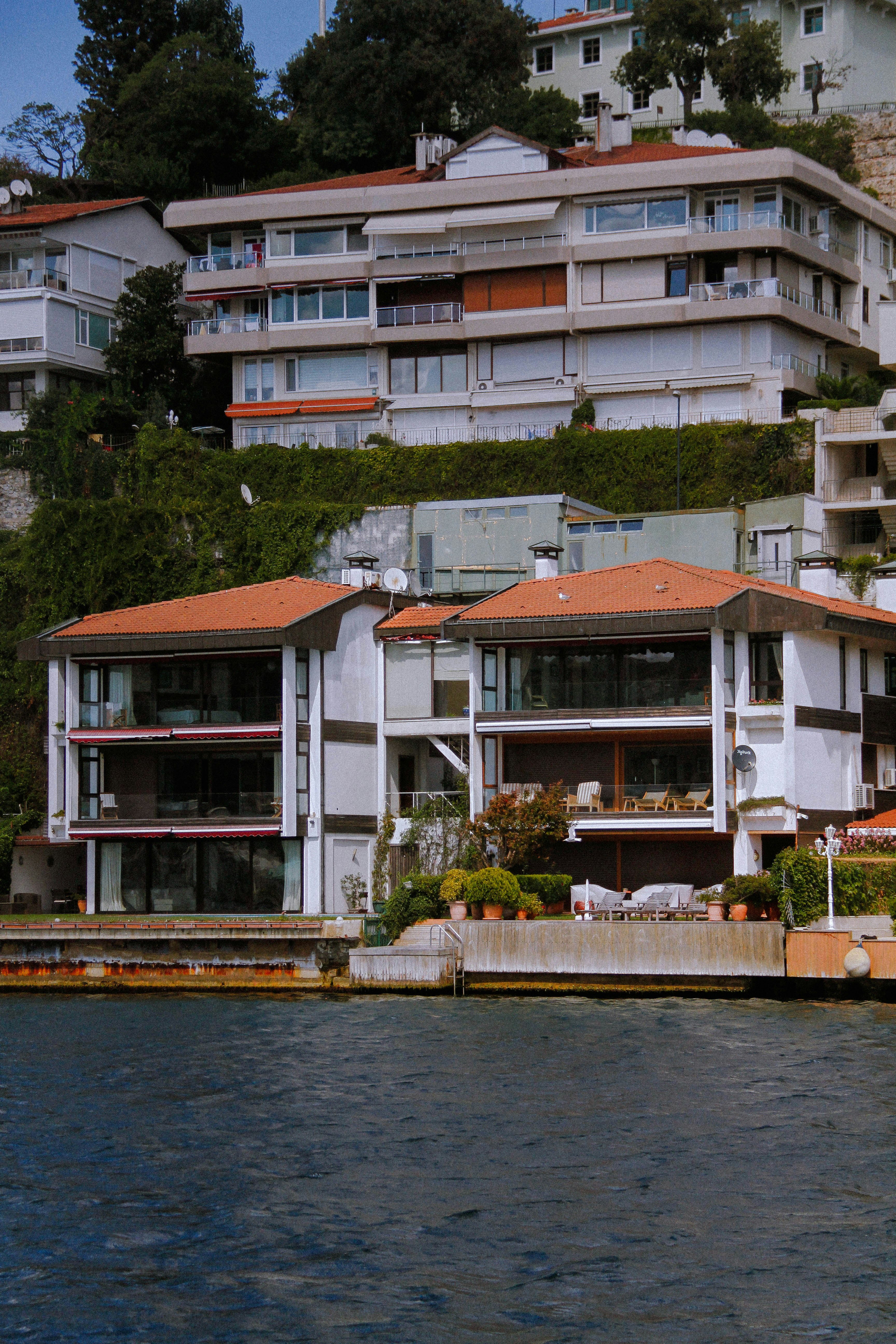 white and brown concrete house beside body of water during daytime
