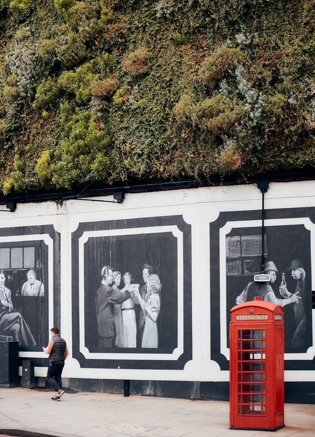 2 men sitting on bench in front of red and white wall with paintings