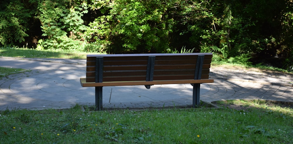 brown wooden bench near green trees during daytime