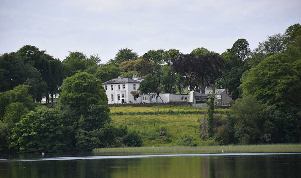 white concrete building near green trees and lake during daytime