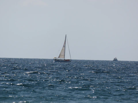 Yacht sailing smoothly on deep blue sea under clear sky