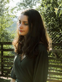 A candid shot of a woman enjoying a peaceful moment in a sunlit garden, embodying calm and confidence.
