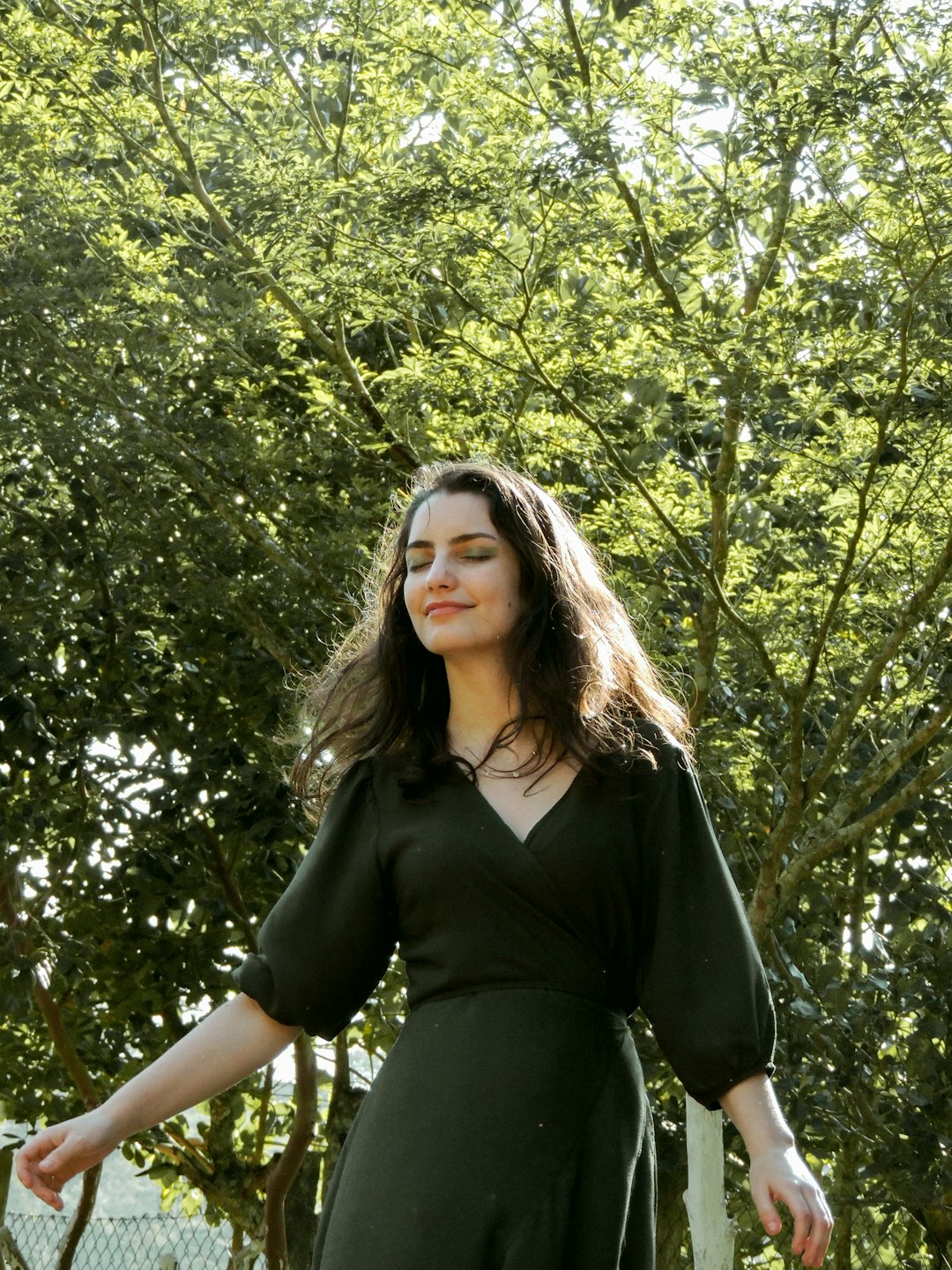 woman in black dress standing near green tree during daytime