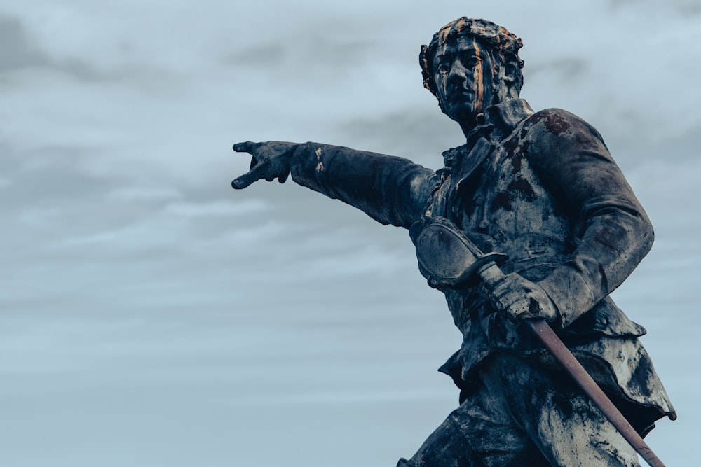 man holding stick statue during daytime