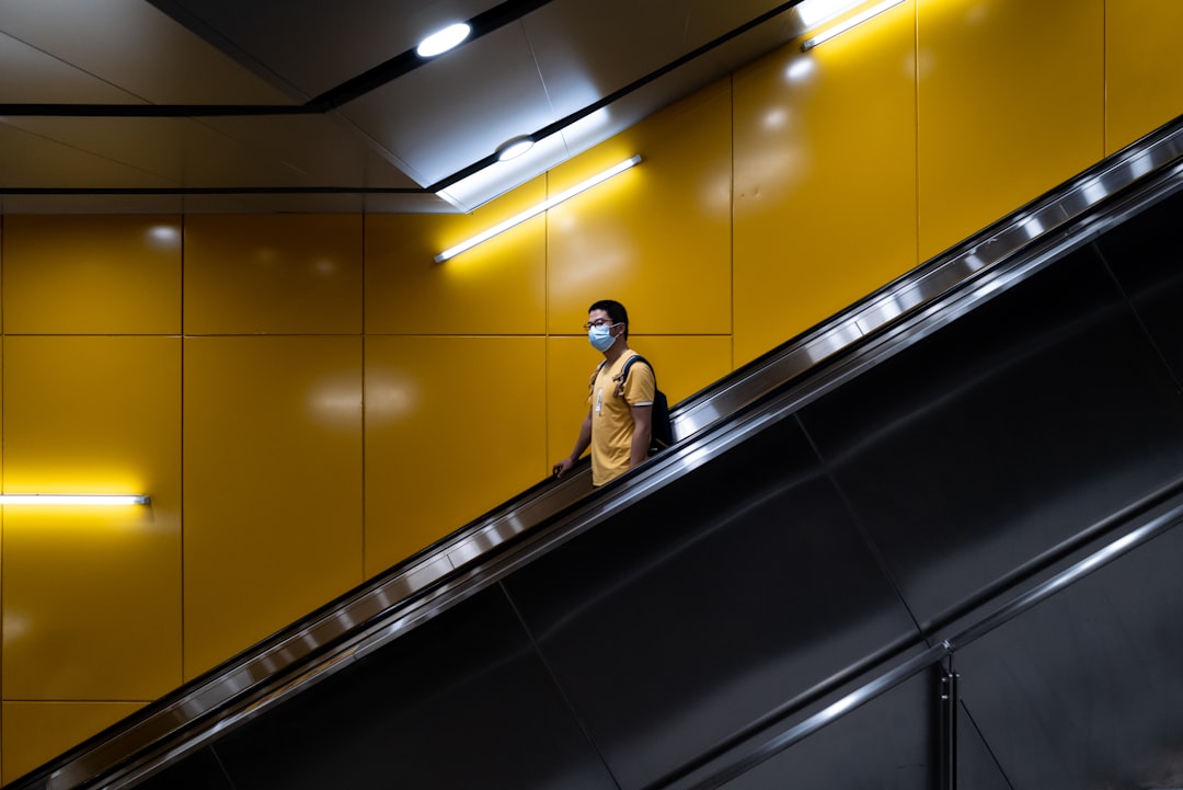man in brown coat standing on escalator