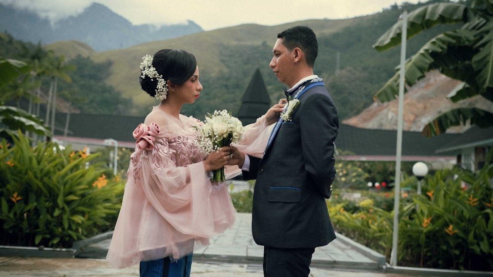 man in black suit holding woman in pink dress