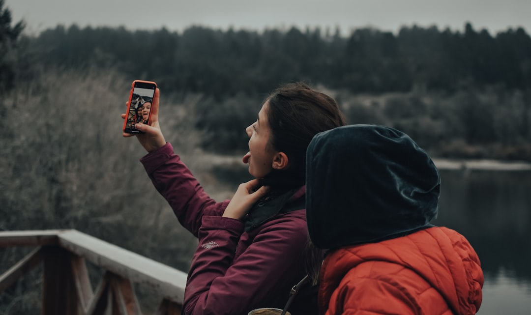 woman in red jacket holding smartphone