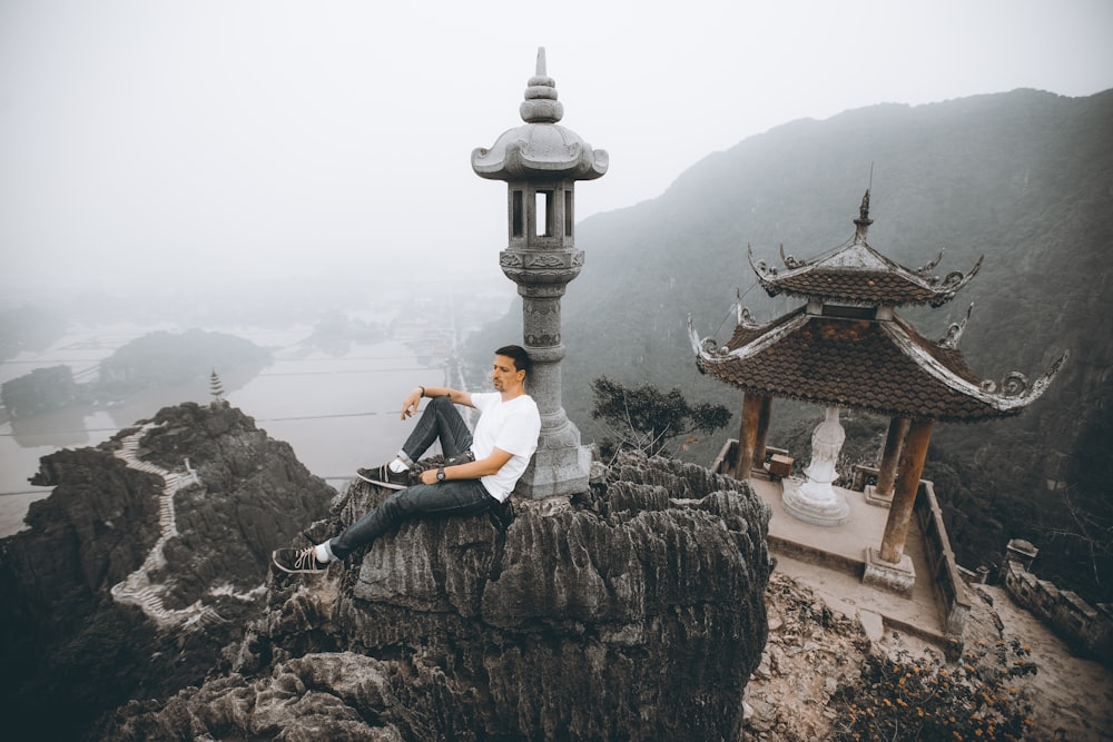 man in black jacket sitting on rock during daytime