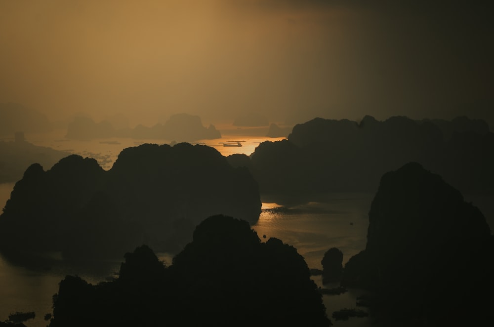 silhouette of rocks on body of water during sunset