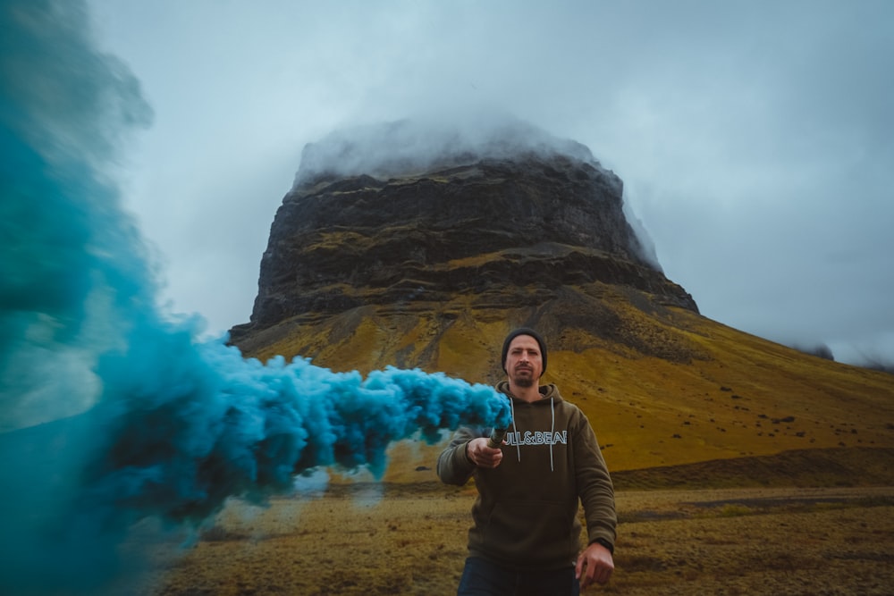 hombre con chaqueta negra sosteniendo un humo verde