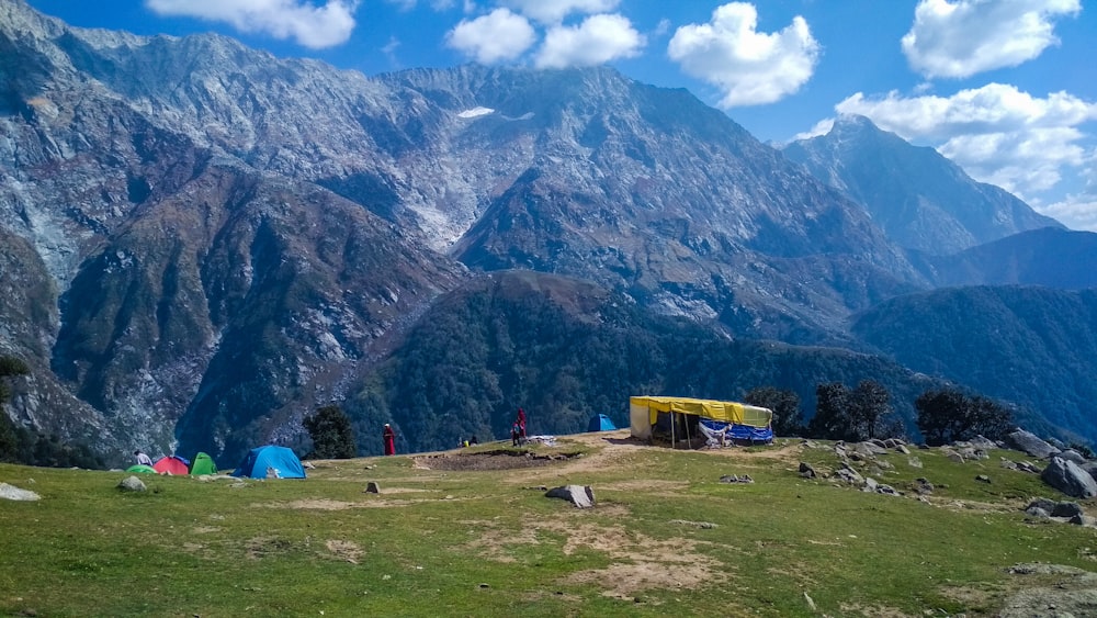 blue tent on green grass field near mountain during daytime