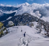 person in black jacket and black pants standing on snow covered mountain during daytime