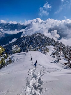 person in black jacket and black pants standing on snow covered mountain during daytime