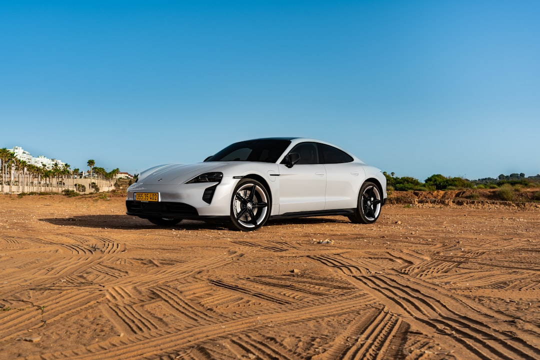 white coupe on brown sand under blue sky during daytime
