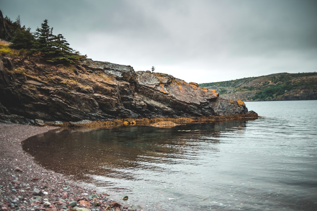 brown rock formation on body of water under white sky during daytime