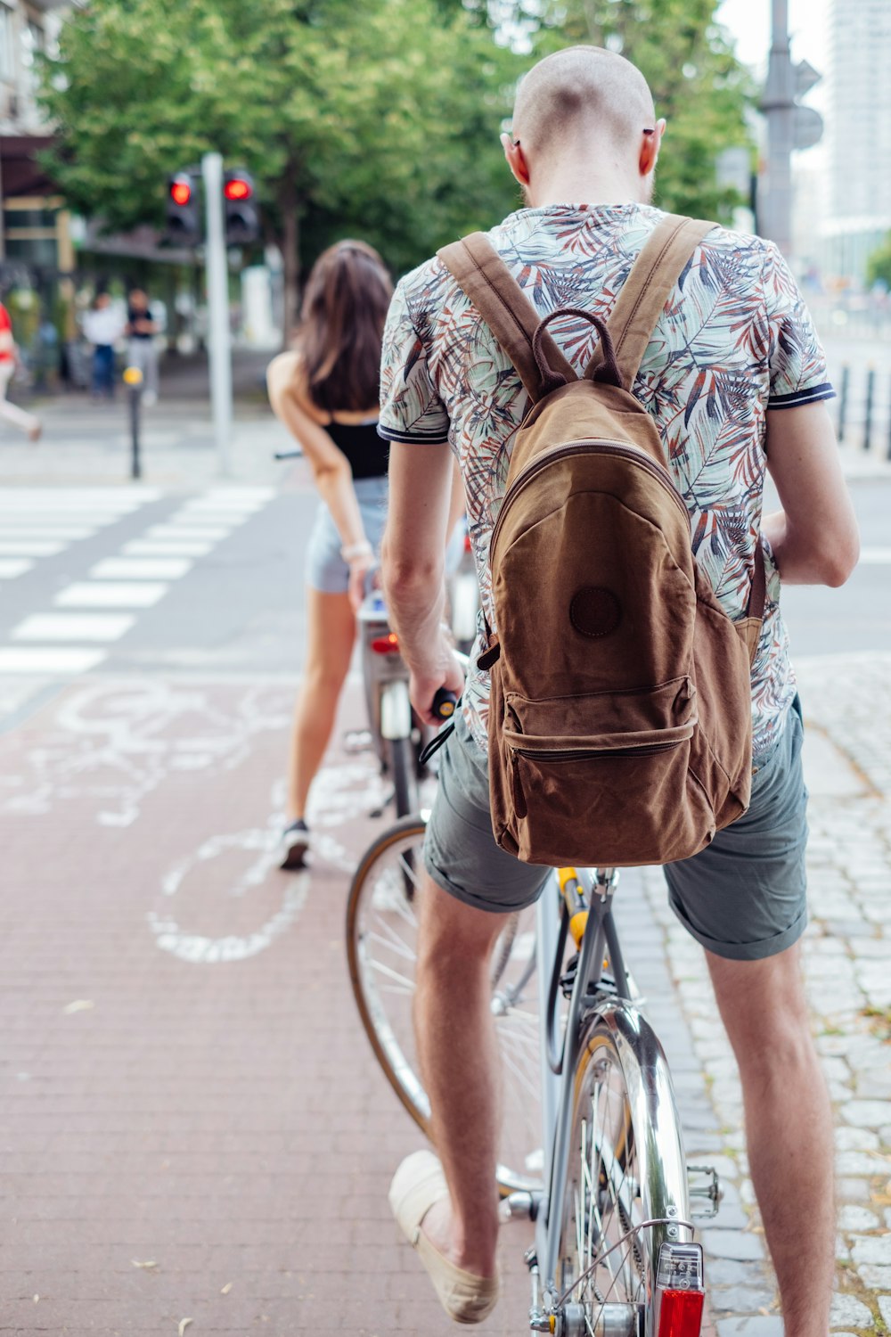 man in brown t-shirt riding bicycle on road during daytime