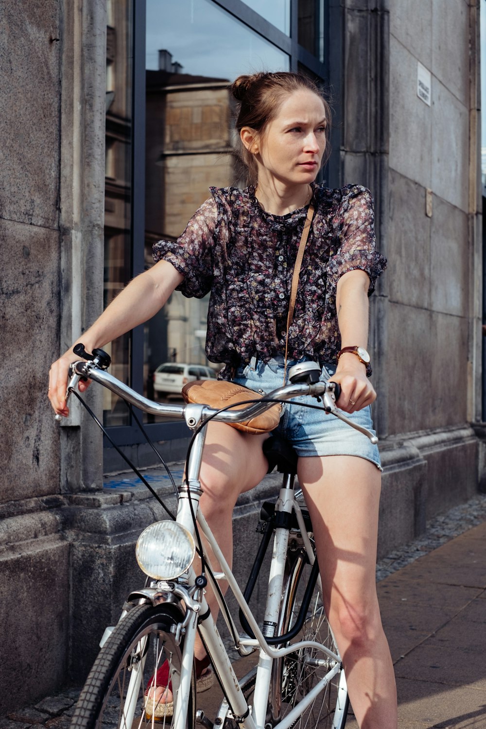 woman in black and white floral shirt and blue denim shorts riding on bicycle