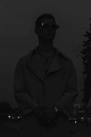 A private detective discreetly observing a subject in an urban setting at dusk.