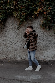 woman in black and brown stripe long sleeve shirt and blue denim jeans standing beside gray
