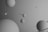 Multiple spheres of various sizes float against a gradient gray background. Some of the spheres are encircled by rings, reminiscent of planets and their rings in a stylized solar system depiction.