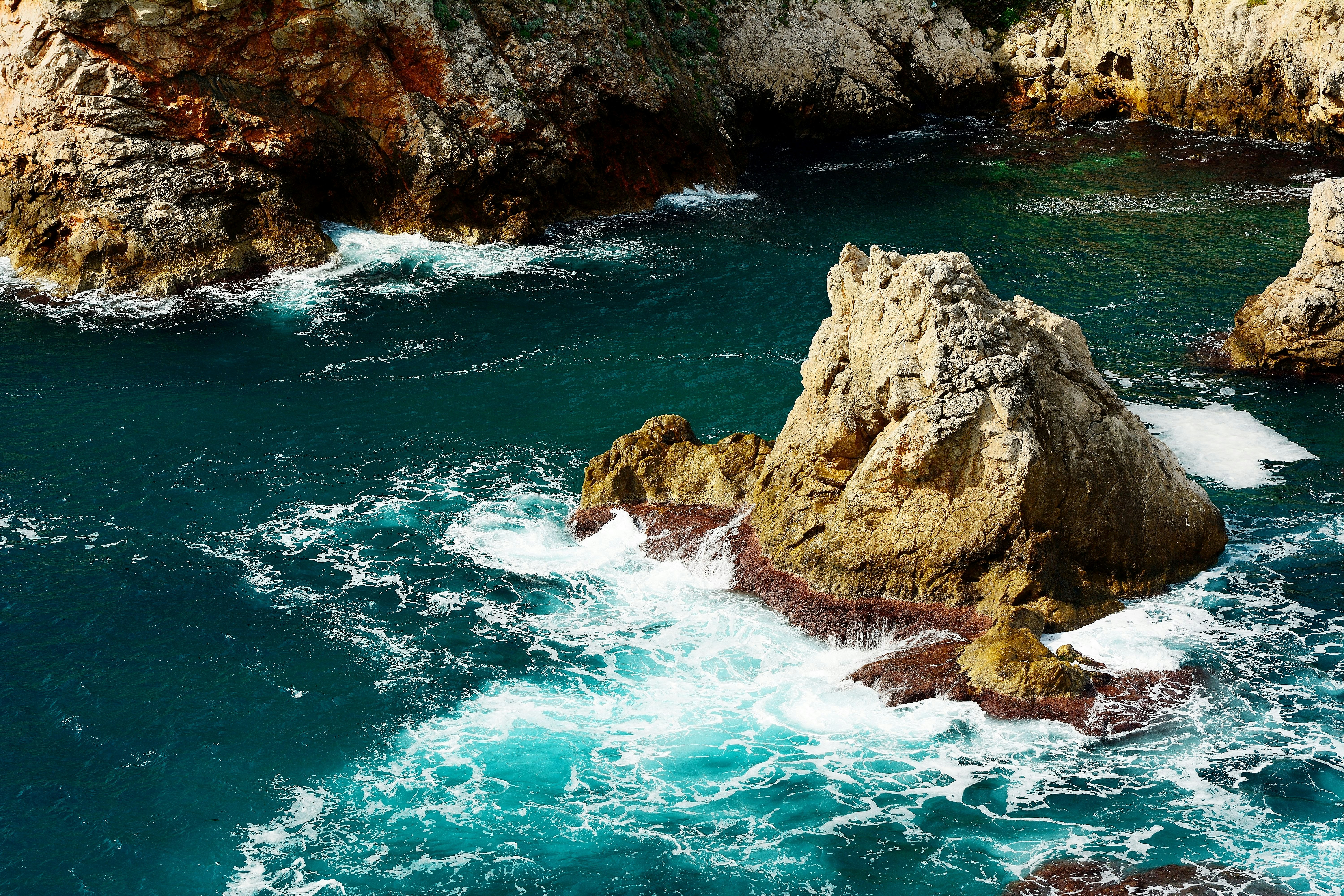 brown rock formation on body of water during daytime