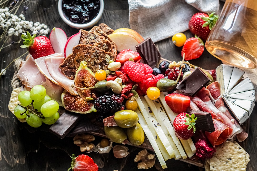 sliced fruits on white ceramic plate, Grazing platter - Cheese & Charcuterie board