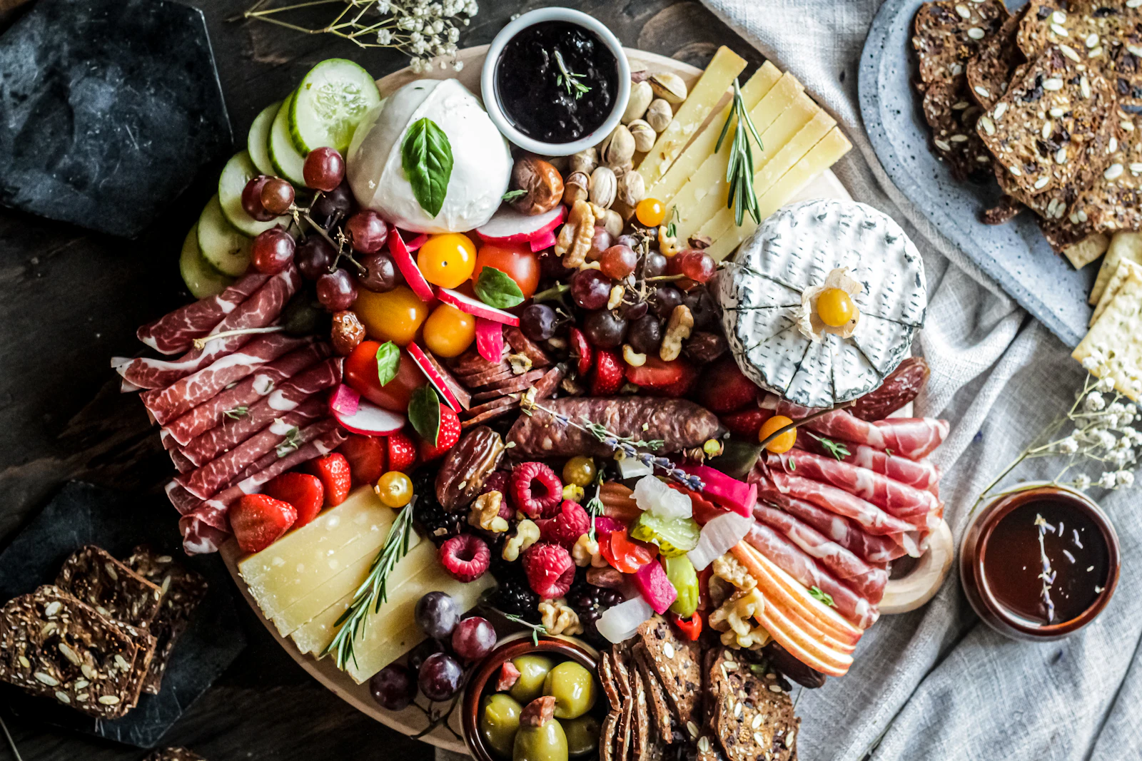 Long holiday grazing table styled with cheeses, fruit and greenery