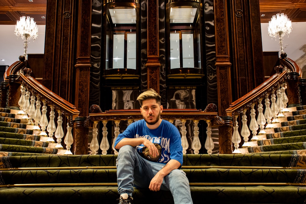 man in blue long sleeve shirt sitting on brown concrete staircase