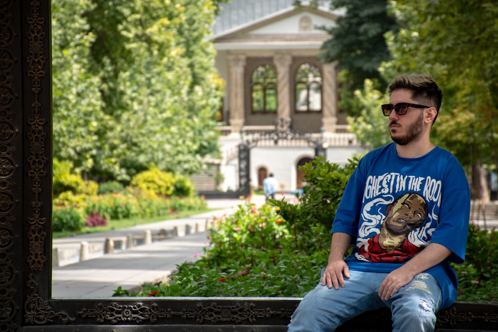 man in blue crew neck t-shirt and blue denim jeans sitting on black bench during
