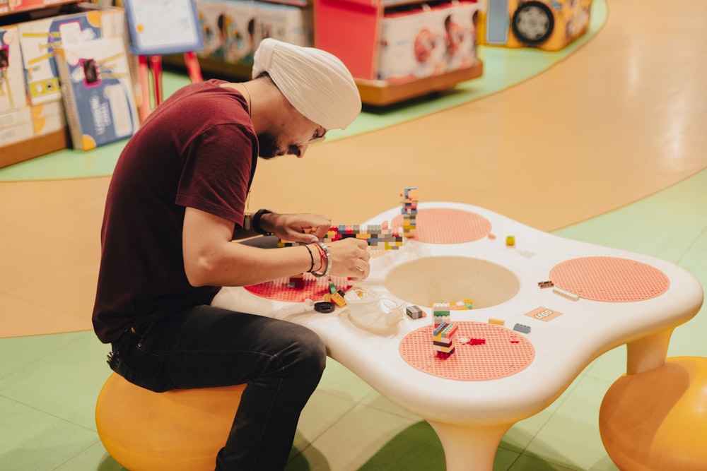 man in red shirt and blue denim jeans sitting on white round table