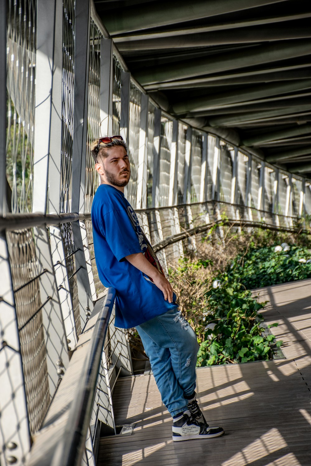 man in blue long sleeve shirt and blue denim jeans standing on gray concrete stairs