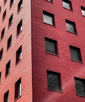 Image showing a commercial building facade made with red bricks and large windows.