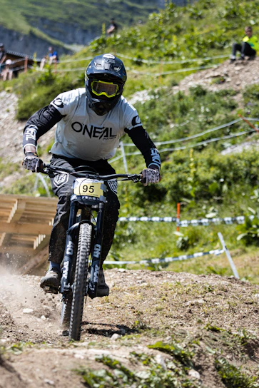 man in black and white motorcycle suit riding on black mountain bike during daytime
