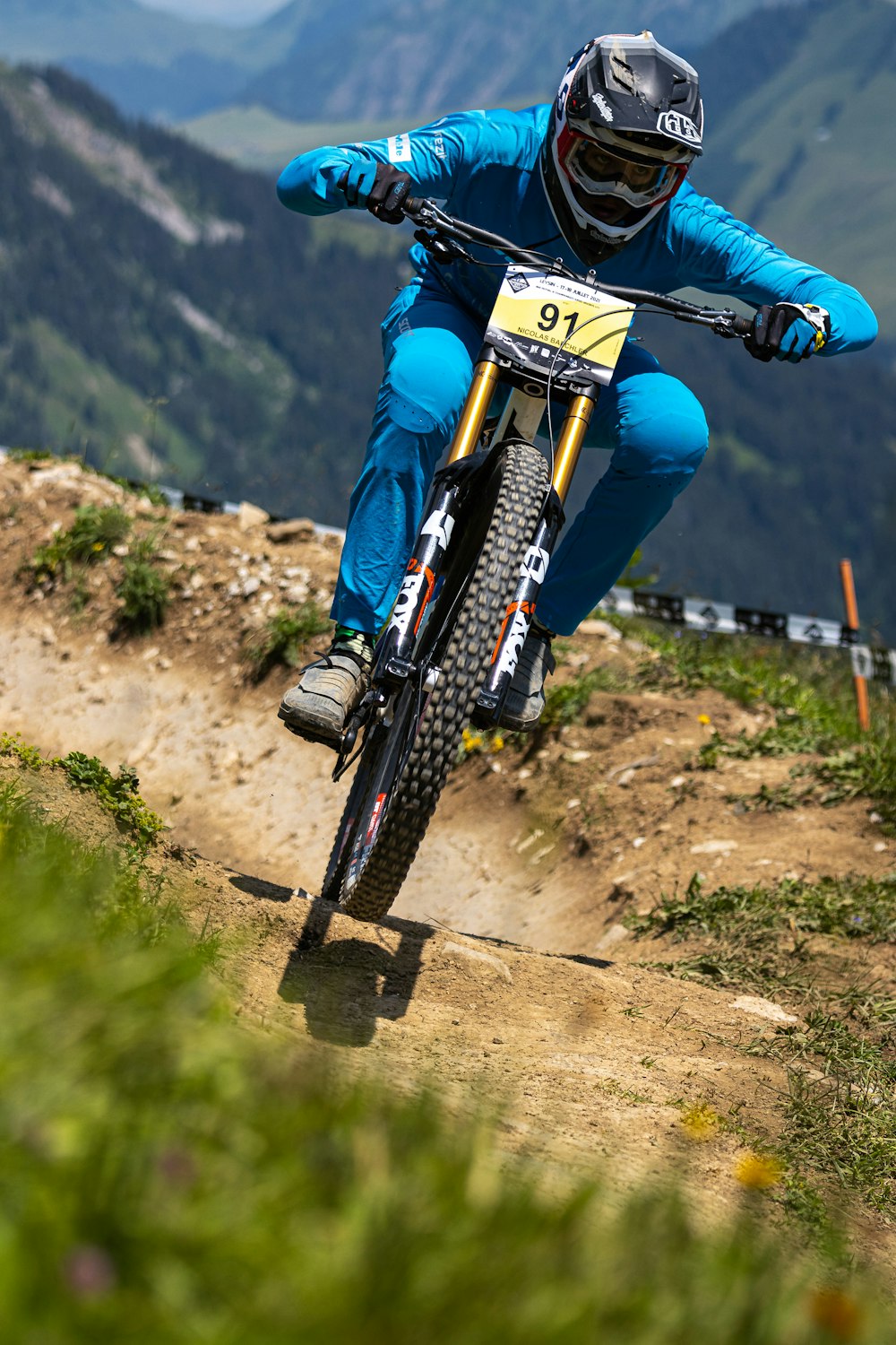 man in blue and white motocross helmet riding on black mountain bike during daytime