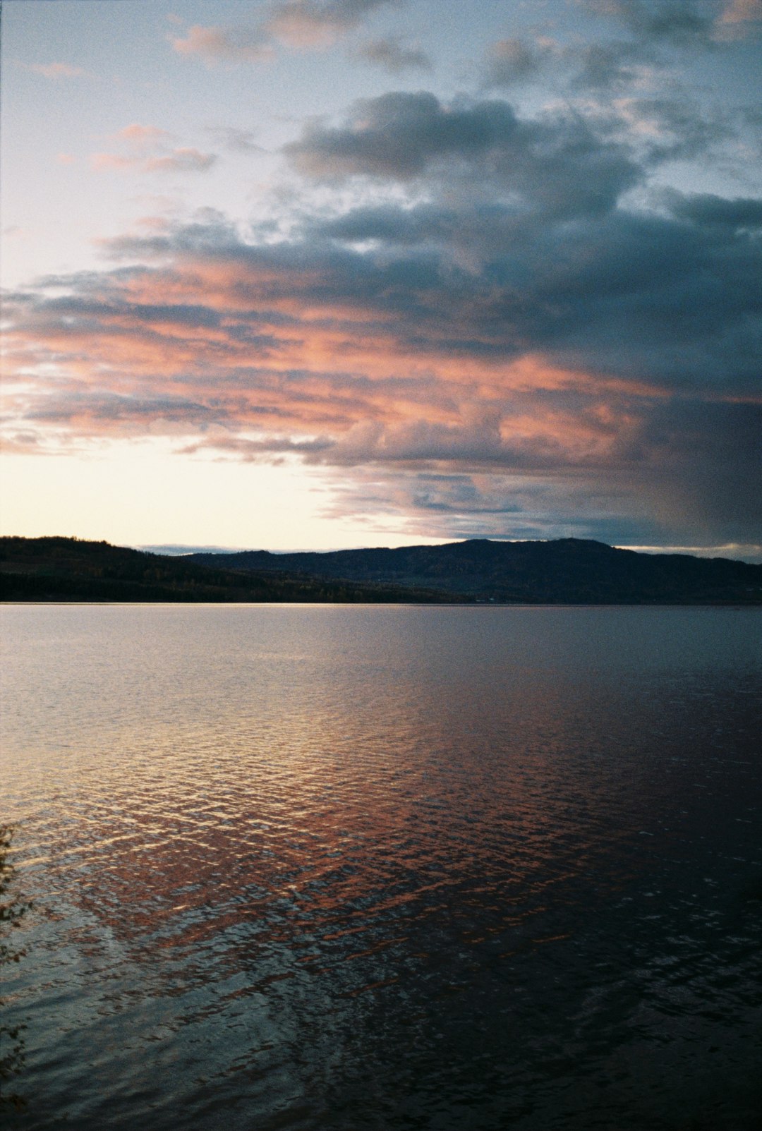 body of water near mountain during sunset