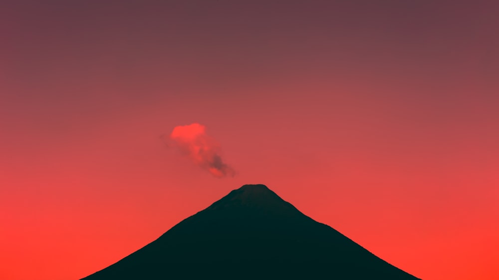 silhouette of mountain under cloudy sky during daytime