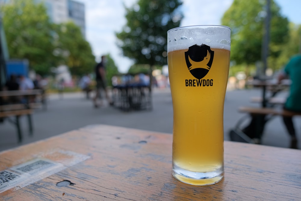 clear drinking glass with beer on brown wooden table