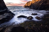 brown rocky mountain beside body of water during sunset