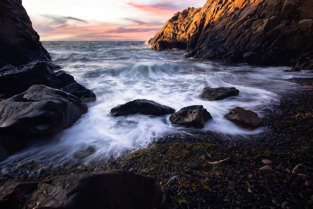 brown rocky mountain beside body of water during sunset