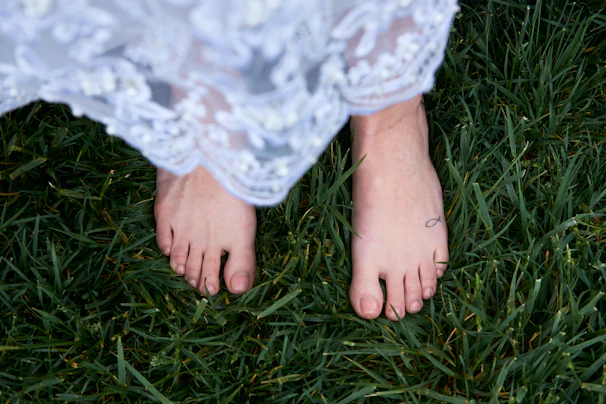 Woman walking barefoot on grass wearing a silver anklet with intricate design
