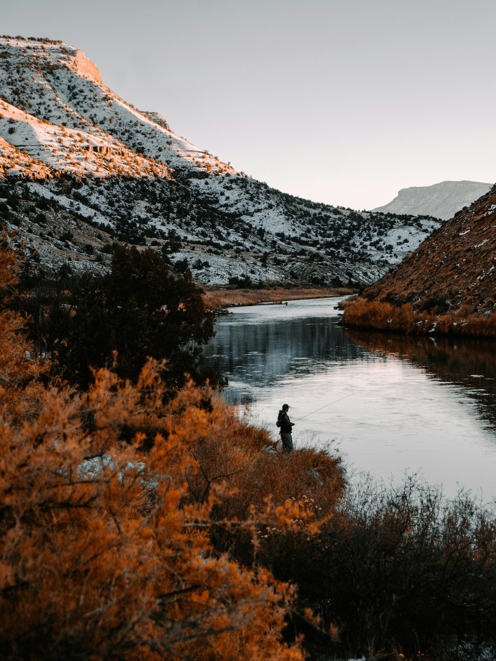 personne debout sur le lac près d’une montagne enneigée pendant la journée