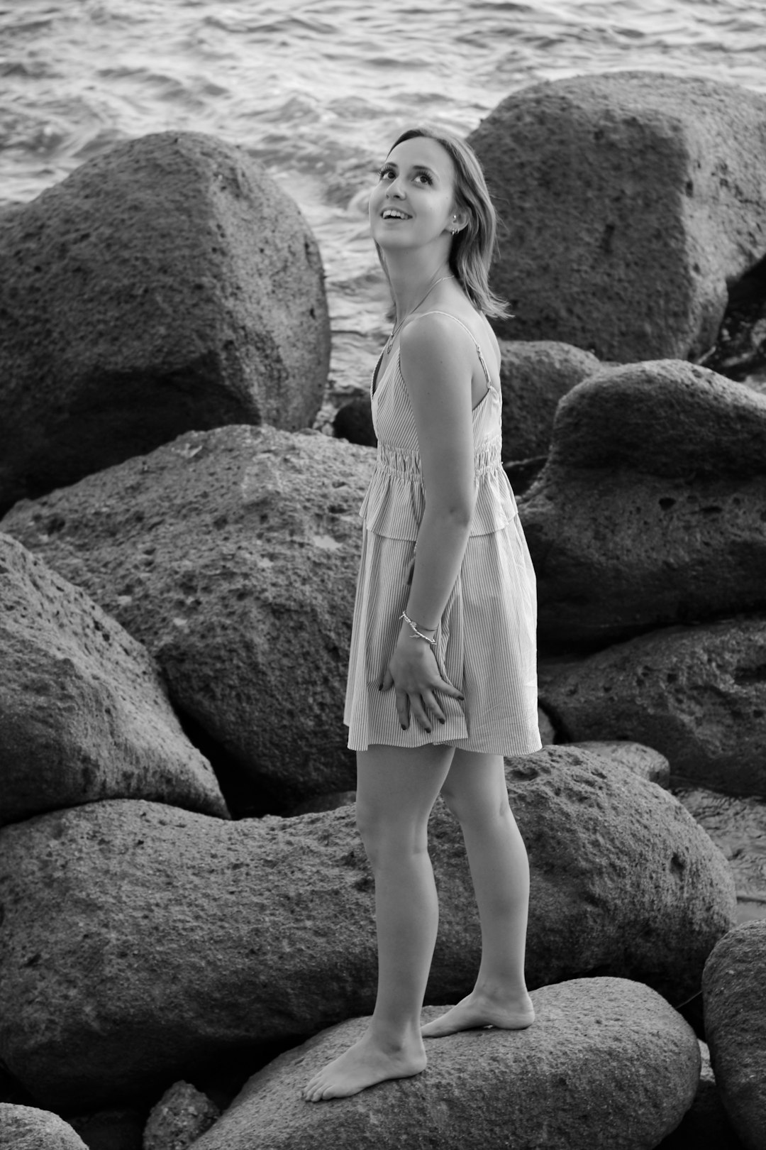 woman in white spaghetti strap dress standing on rock