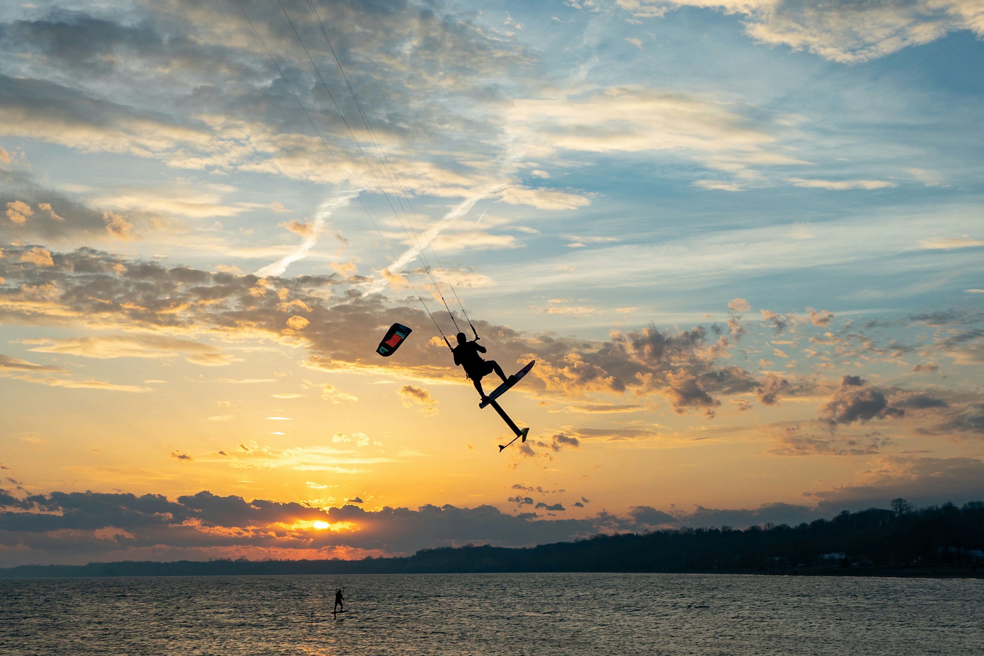 person in black and white shorts riding on black and white kite surfing during sunset