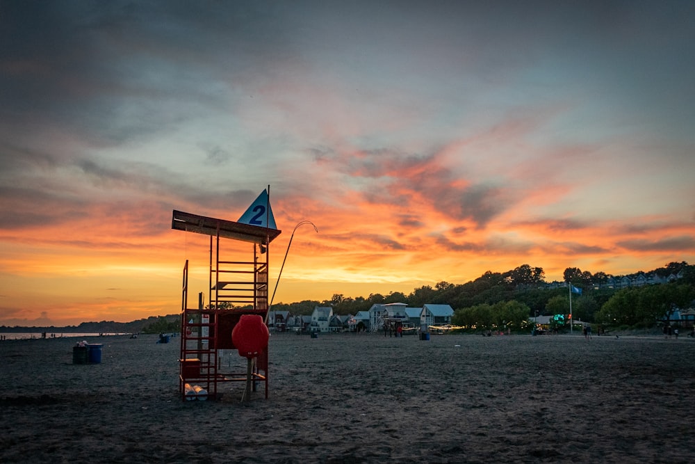 Roter hölzerner Rettungsschwimmerturm am Strand bei Sonnenuntergang
