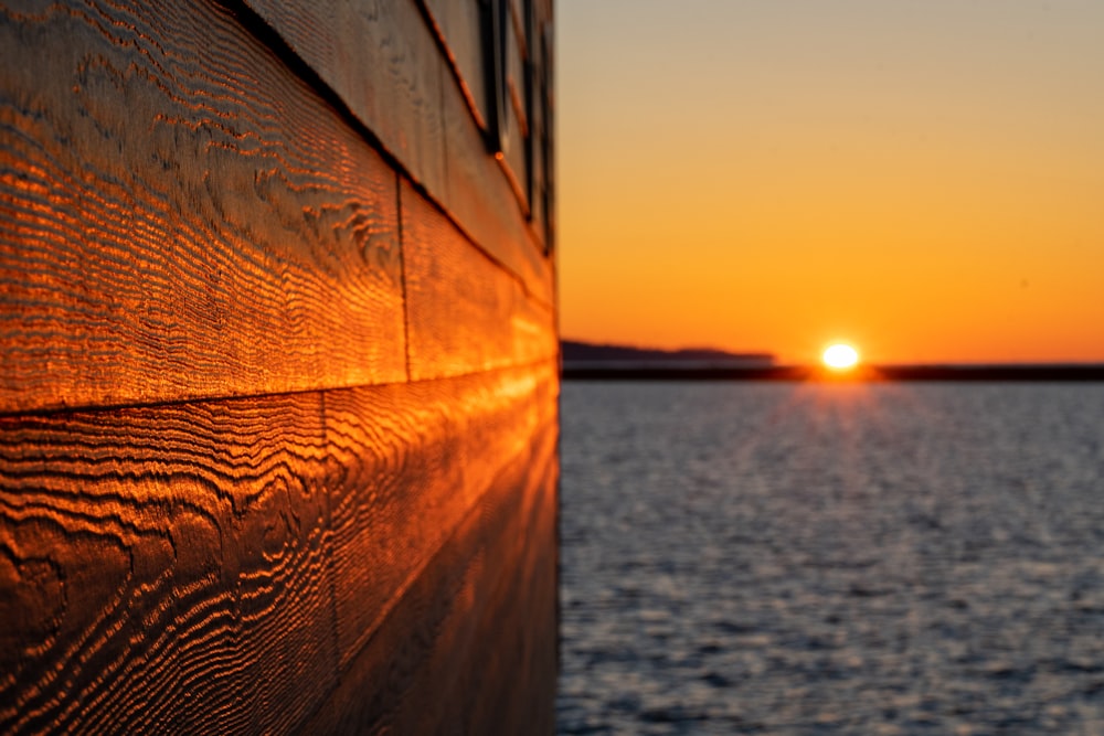 brown wooden fence near body of water during sunset