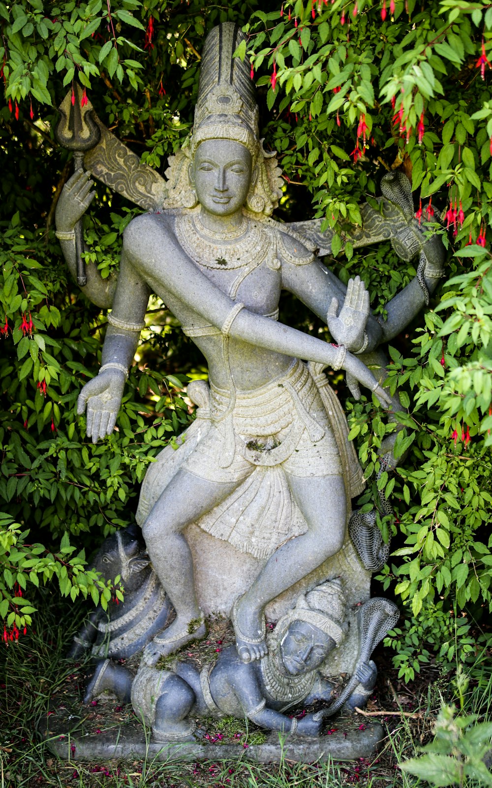 woman in dress statue surrounded by green plants