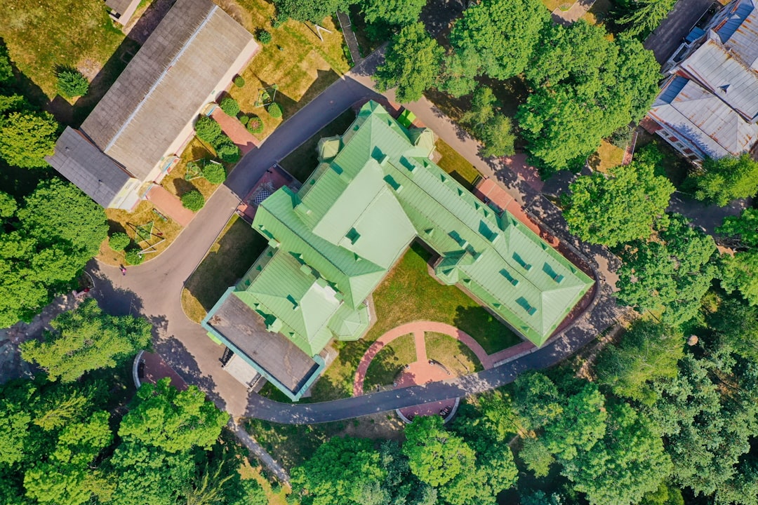 aerial view of green and brown house surrounded by green trees during daytime